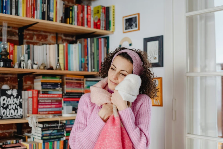 a girl holding a teddy bear in front of a book shelf