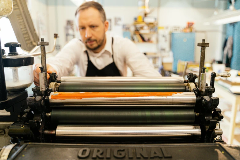 the man is using the machine to print fabric