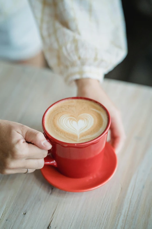 coffee in a red mug sitting on top of a wooden table