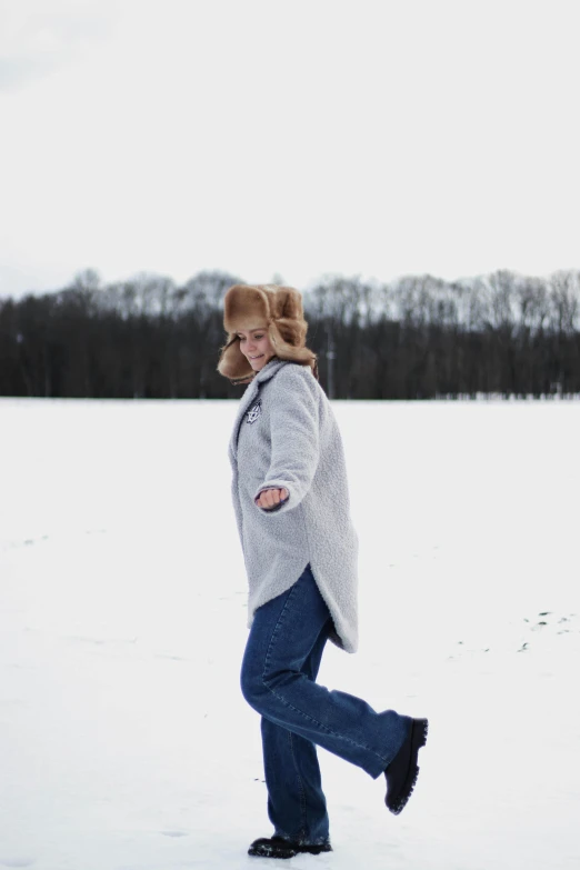 a girl in jeans and a gray sweater is on a snow covered field