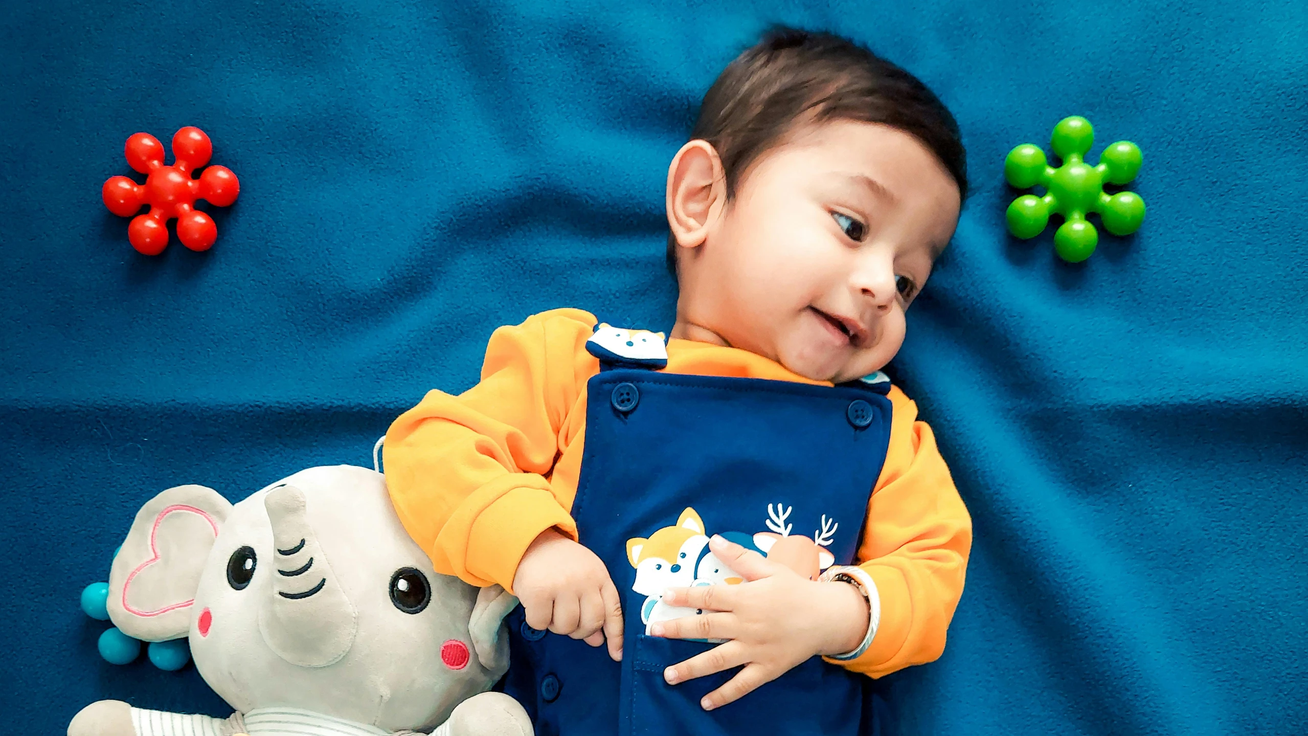 a baby posing for the camera while holding a stuffed animal