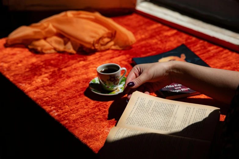 a cup on a red table with an open book