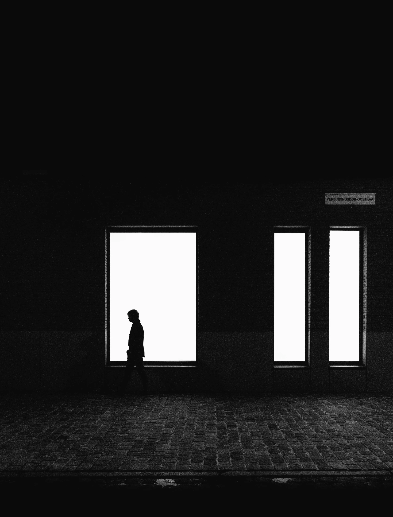 a person walking in the dark near three open windows