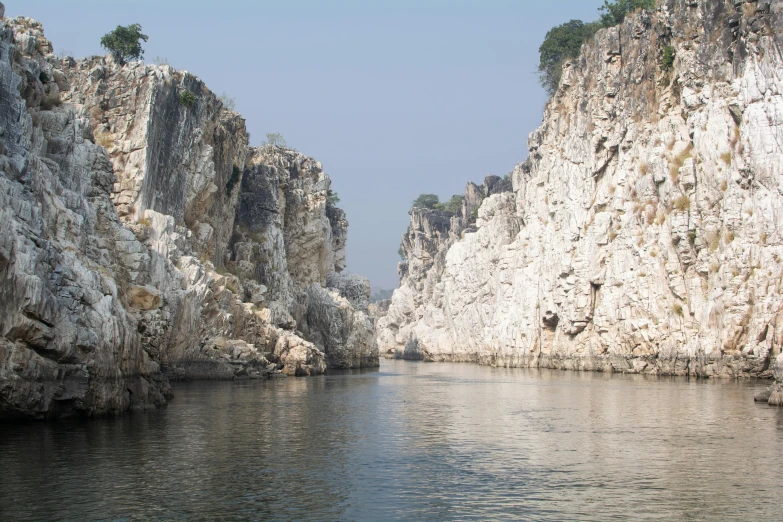 water is reflecting the cliff faces, along with trees and bushes