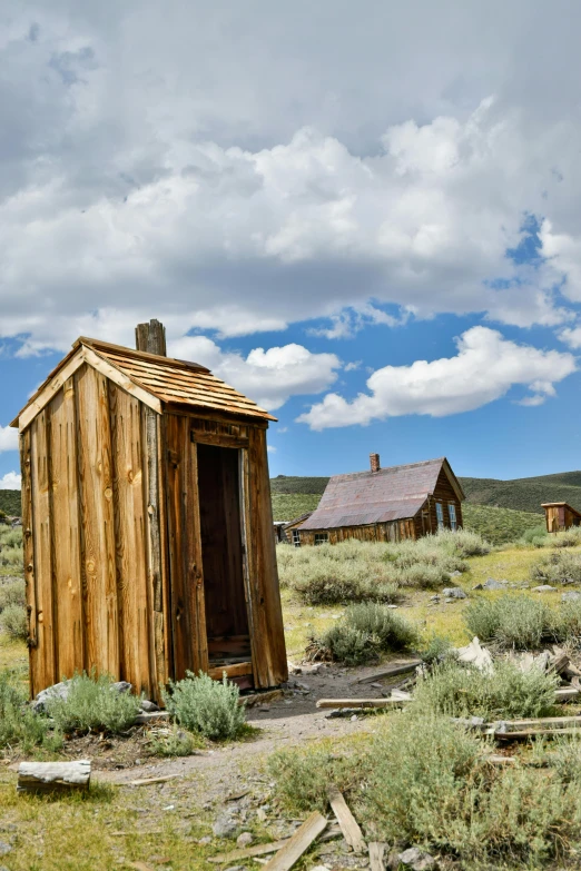 a wooden outhouse sitting in a grass field