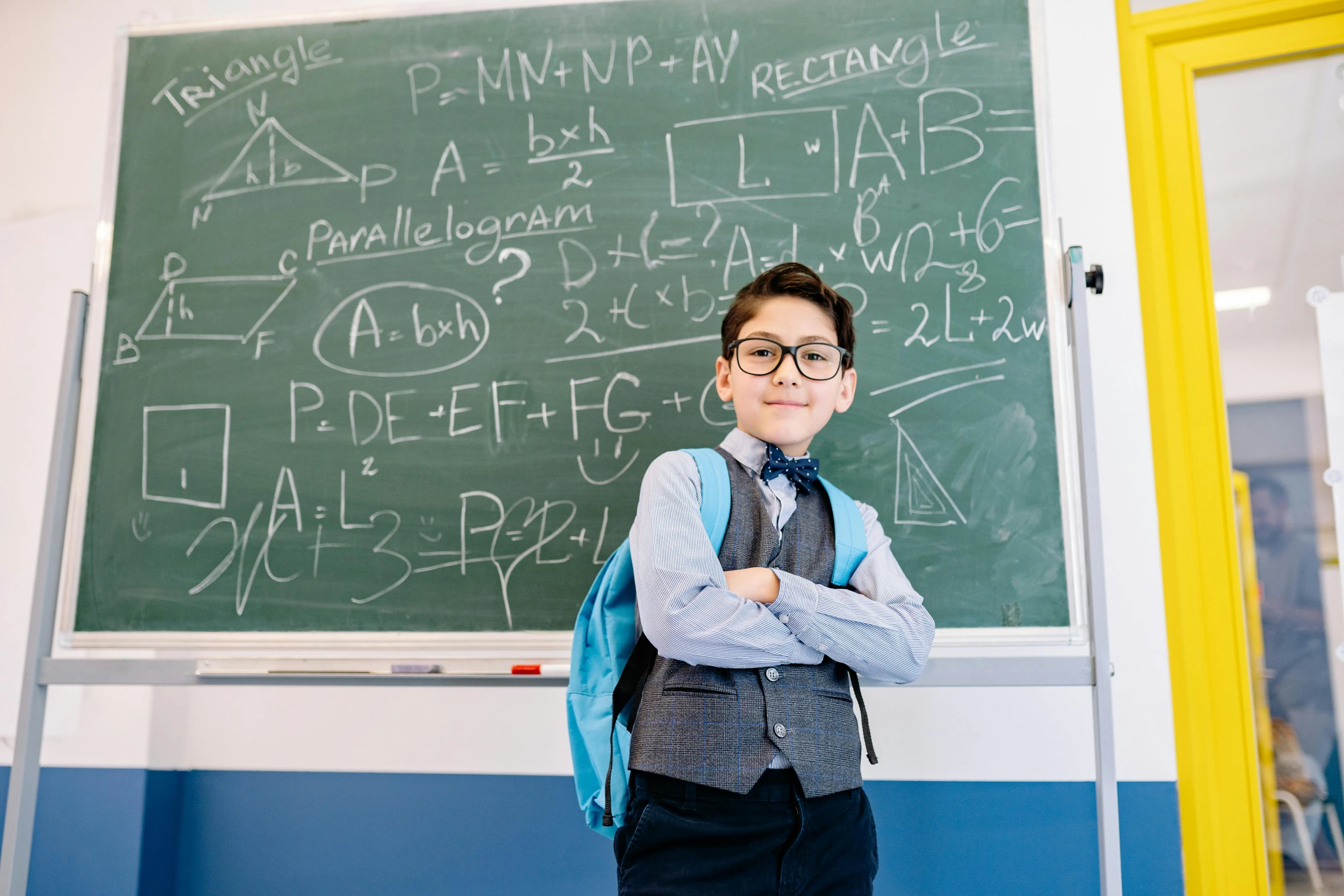  wearing glasses standing in front of chalk board