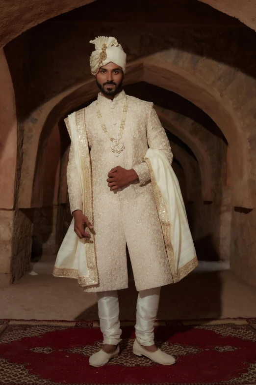 a man in a white wedding shergh standing next to a red carpet