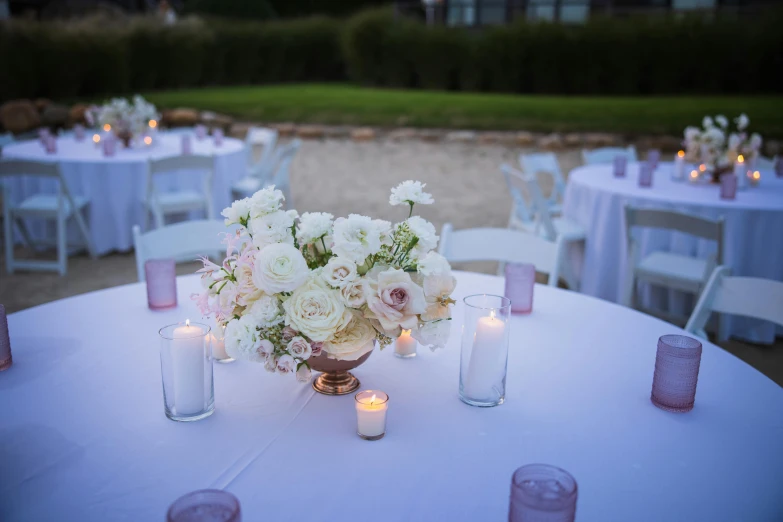 table with white and purple flowers in vases with candles