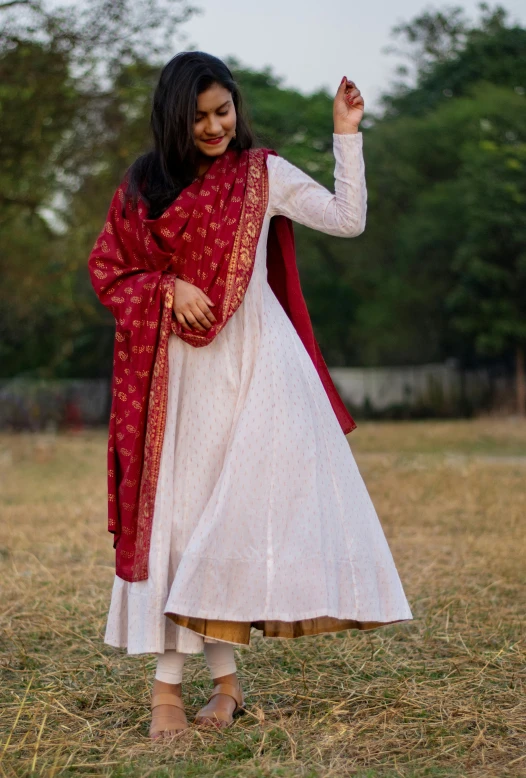 a woman wearing a white and maroon dress in a field