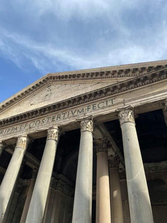 an old building has four white pillars and a decorative inscription