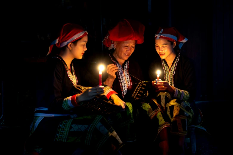 three people in red hat are lighting a candle