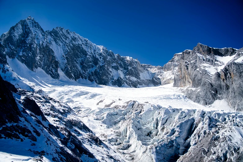 a mountain has snow and some clouds and blue sky