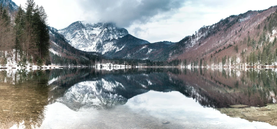 a snowy mountain lake sits below the trees