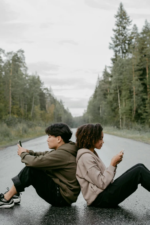 two people sit in the middle of a street while another person sits on the ground