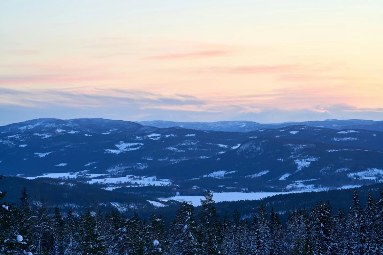 an orange sky with white clouds hangs above the snow - covered mountains