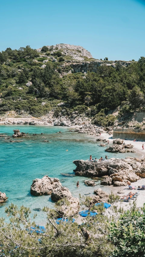 an empty beach with a couple people swimming in the water