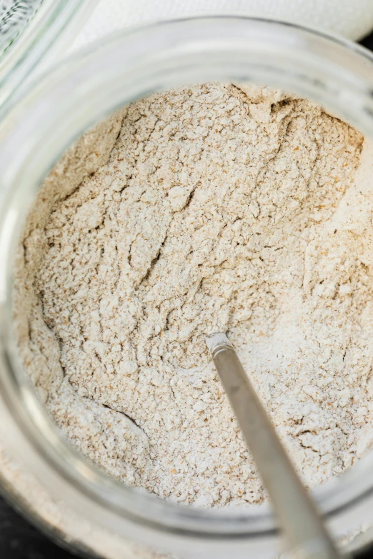 a spoon sits in a large jar containing dry ingredients