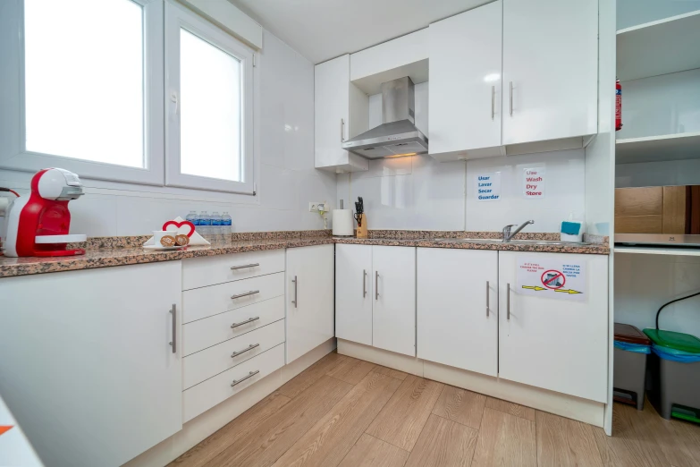 an open kitchen area with white cabinets and light wood flooring