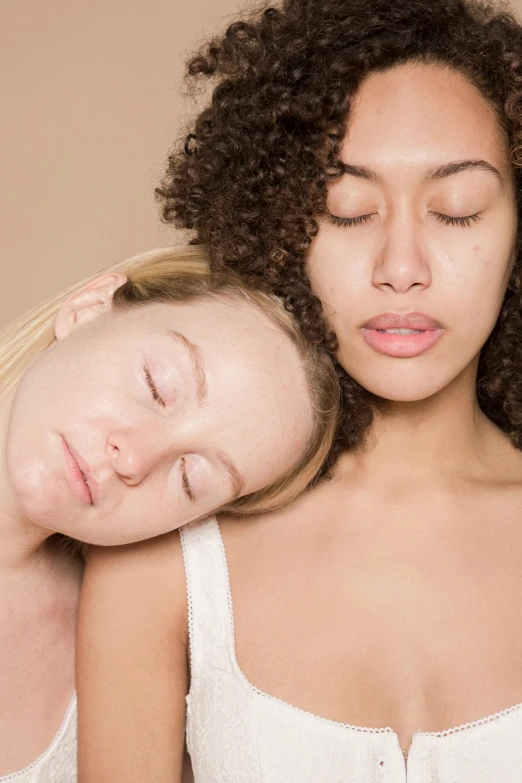 two women one with brown eyes holding her head together