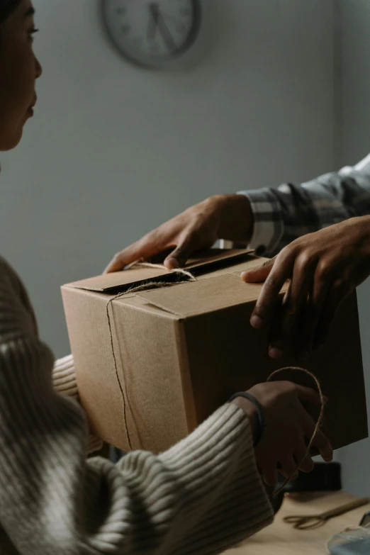 a woman standing at a desk opening a box