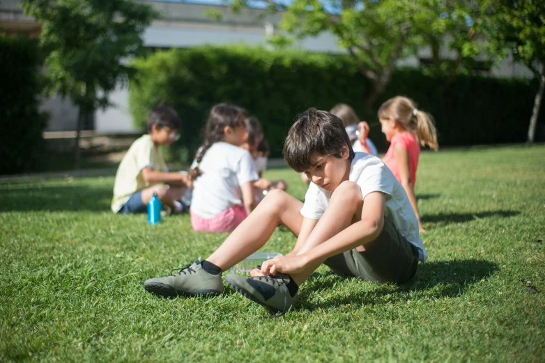 s sitting in the grass and holding on to shoes