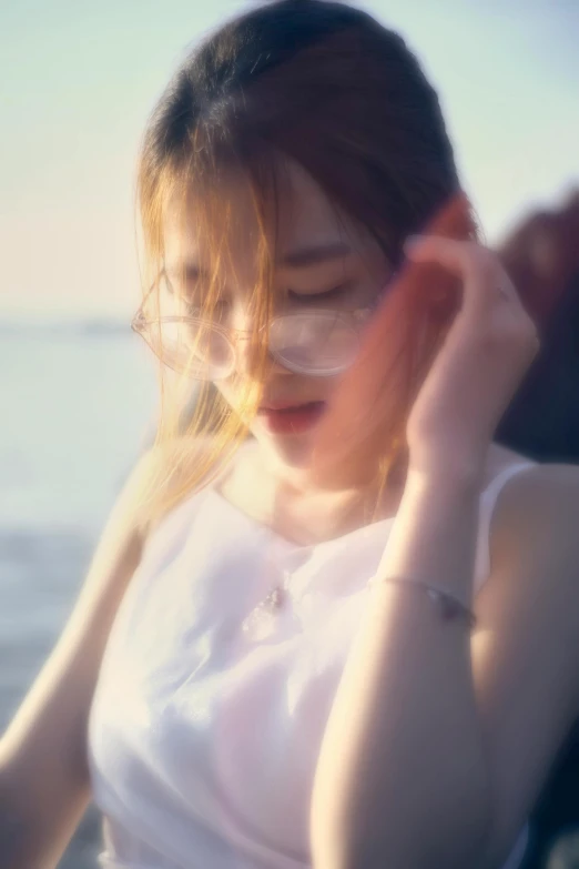 the young woman is holding her ear and looking down at the sand