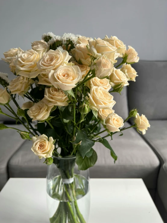 a vase full of beige roses is on a table