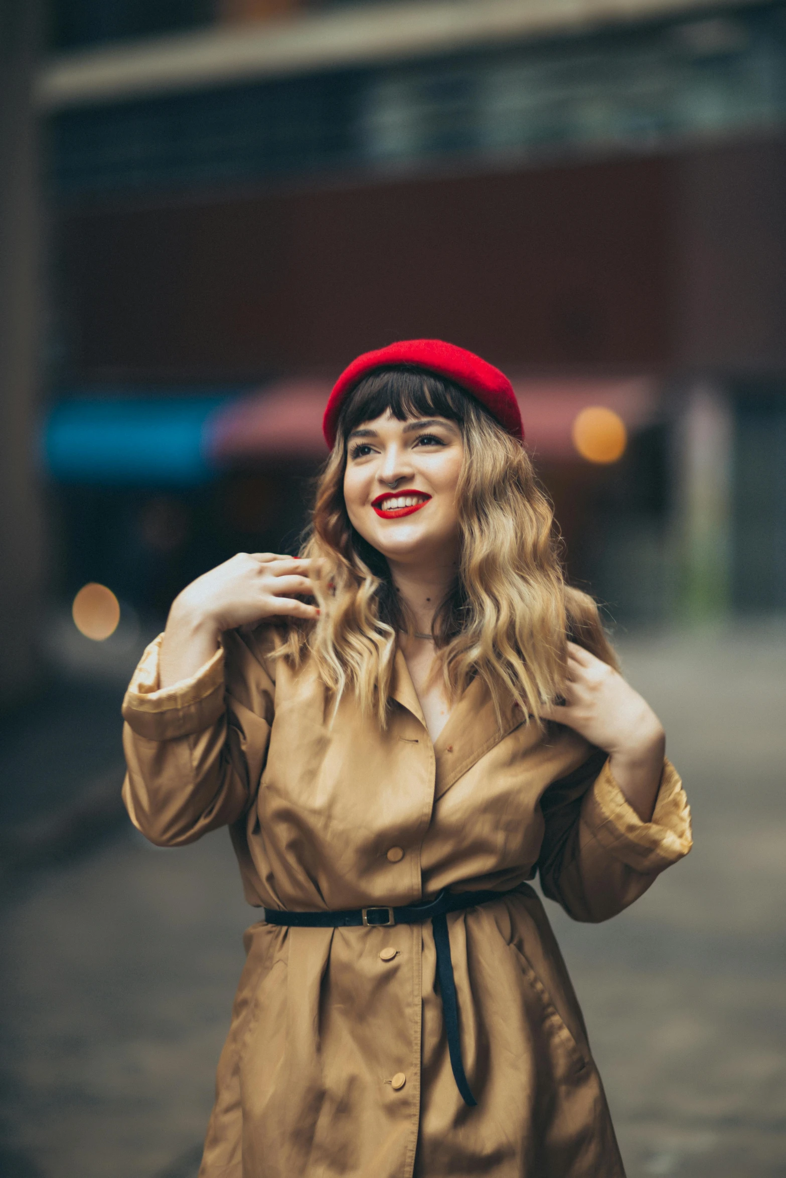 a woman is wearing a tan trench coat and a red hat