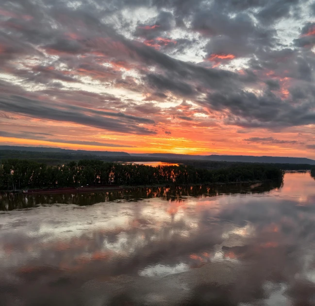 a beautiful sunset over the water with some clouds