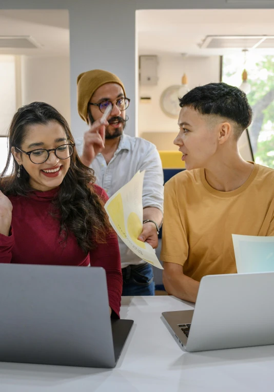 three people working with their laptops in a room