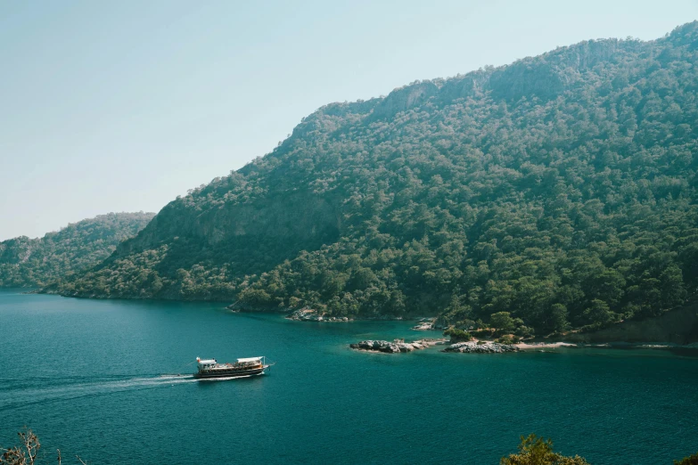 boat sailing on a large river in front of a mountain range