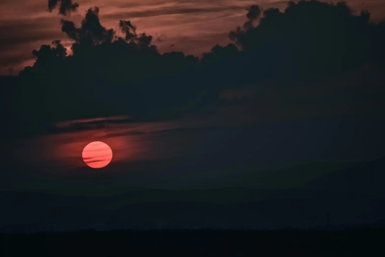 the sun is setting over a field with clouds