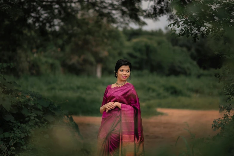 woman in traditional saree in grassy area next to tree