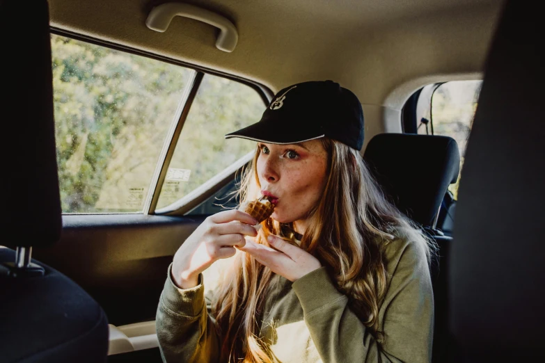 a woman sitting in the back seat eating a doughnut