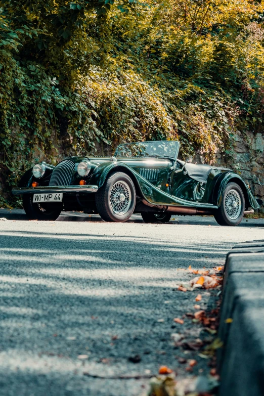 this is an old sports car driving along a road