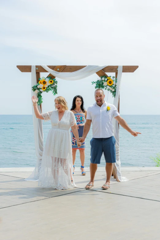 a man and woman stand under a ceremony on the beach