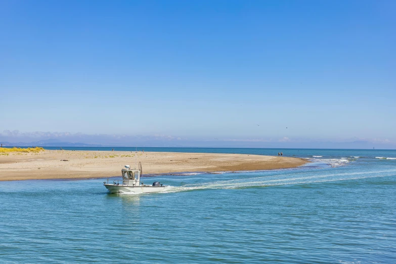 a boat is driving down the water near sand