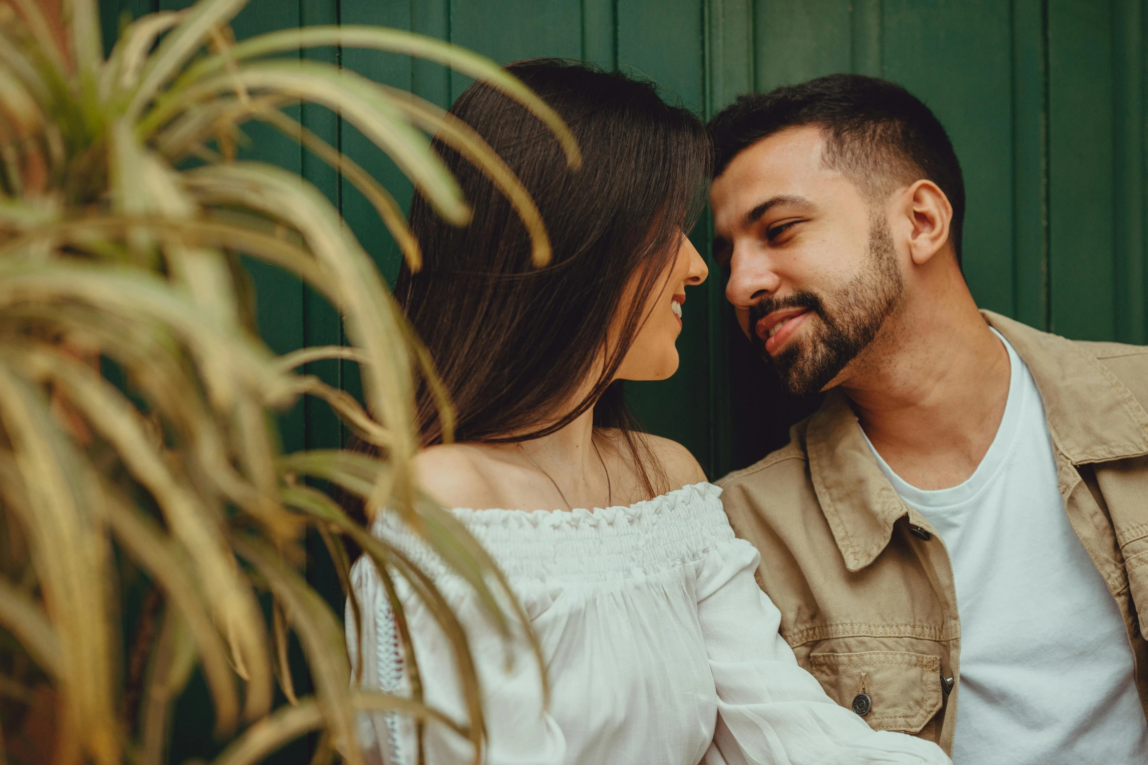 a man and woman sitting in front of a plant