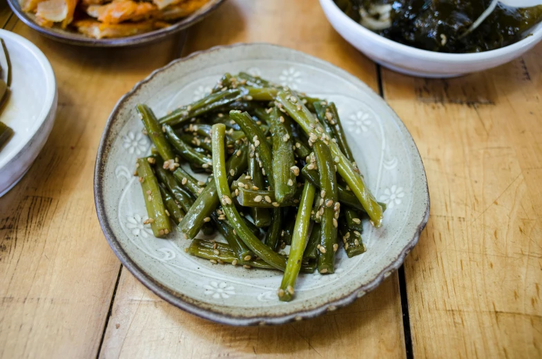 a bowl of stir fried green beans on a table with other food dishes