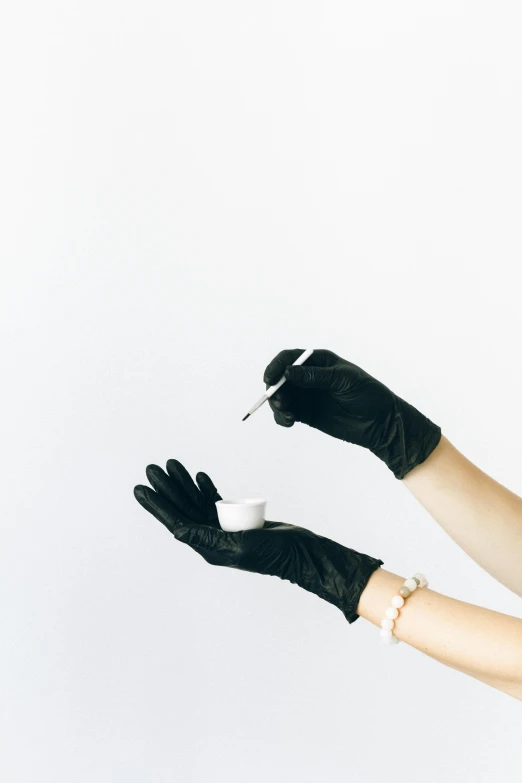 a person wearing black gloves holding a spoon