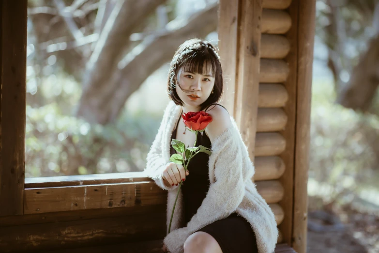 woman in short black dress sitting on porch with flower