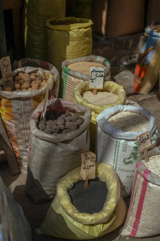 several sacks and baskets of rice on a market stand