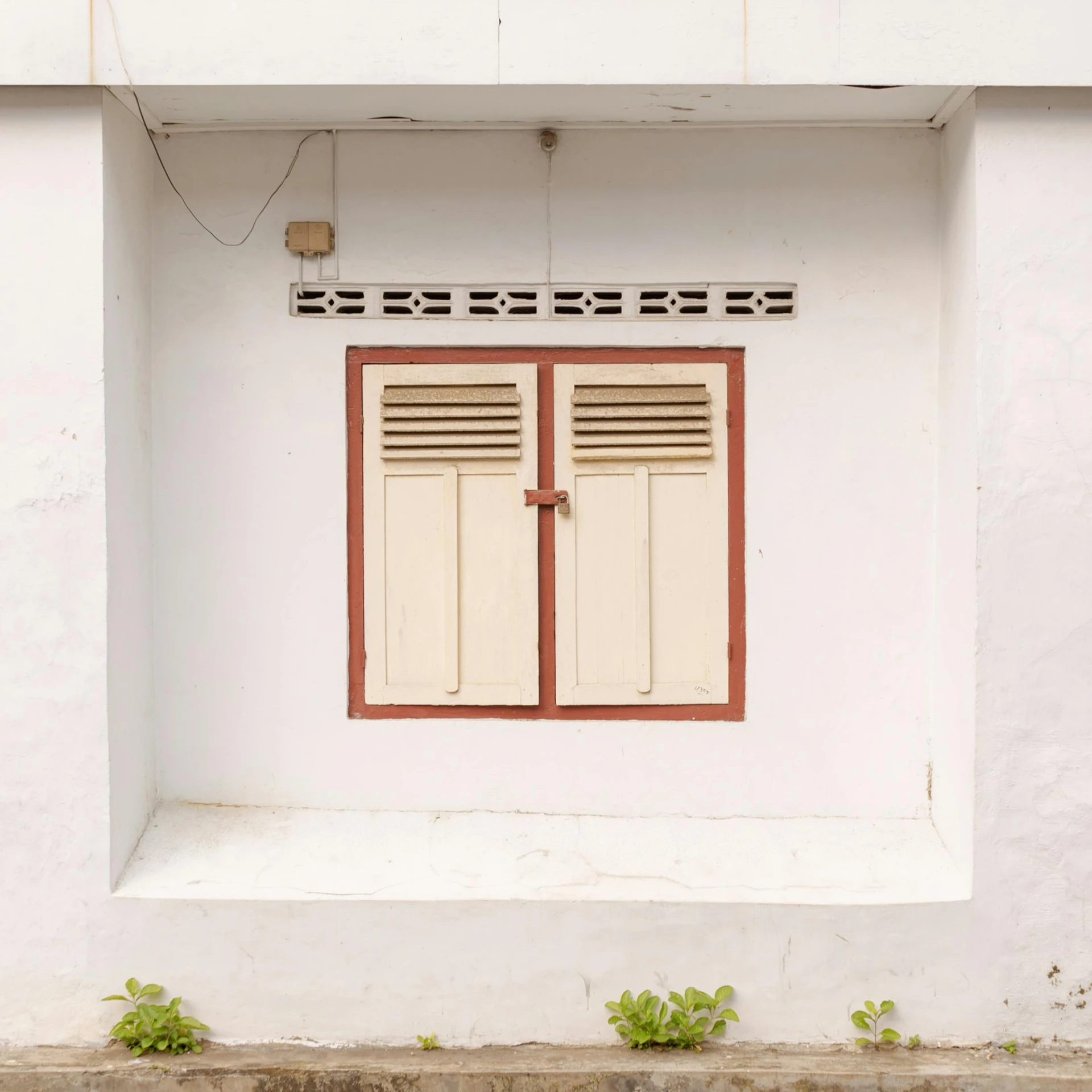 a red and white window with two closed doors on a building