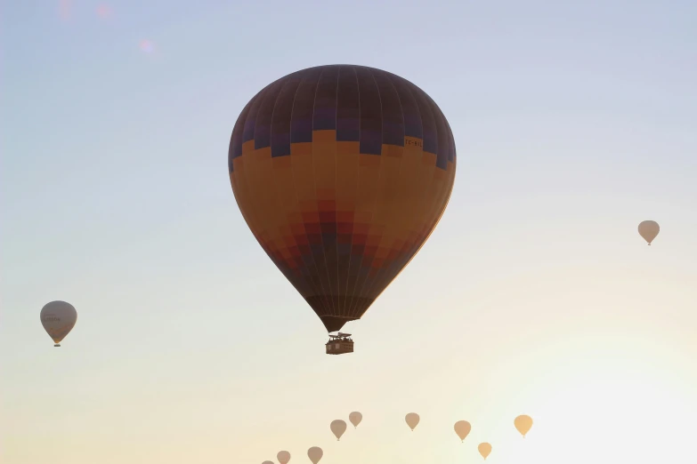 a group of balloons fly through the sky at sunset