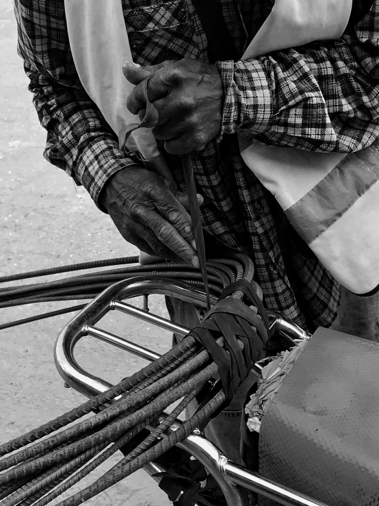 man in plaid shirt with bicycle tire attached to handlebar