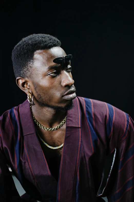 a black male model wearing a striped shirt and earrings