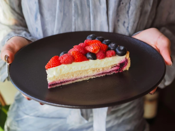 a dessert sitting on a black plate being carried by a person