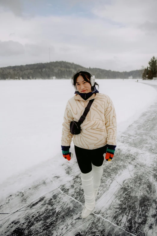 a woman in white jacket walking on snow covered road