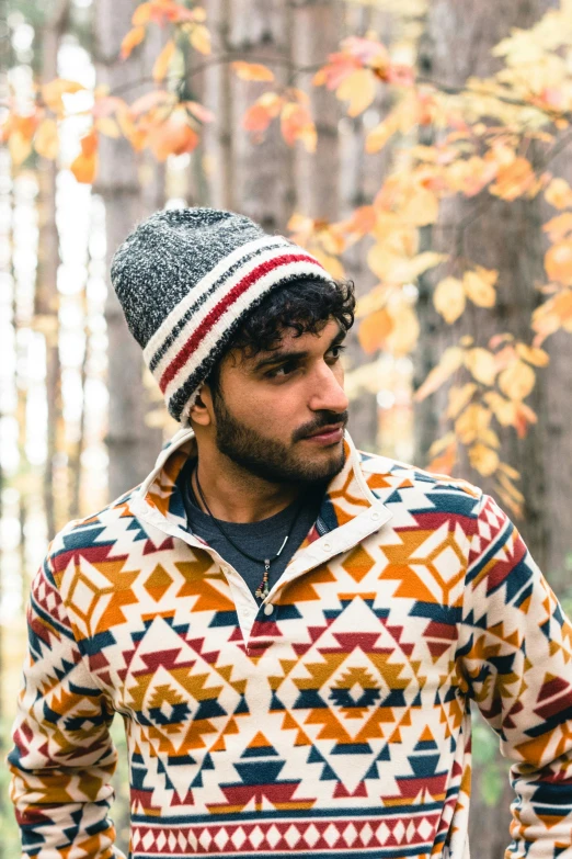 a man with a patterned sweater and hat standing outside