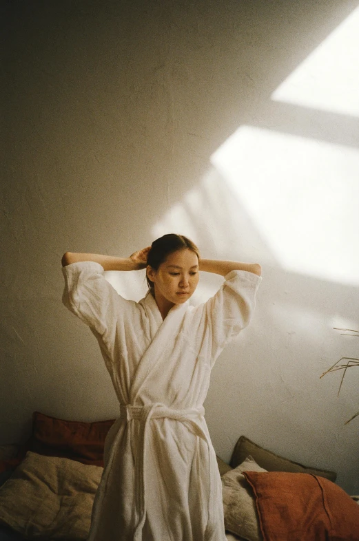 a woman in a bath robe standing next to a window